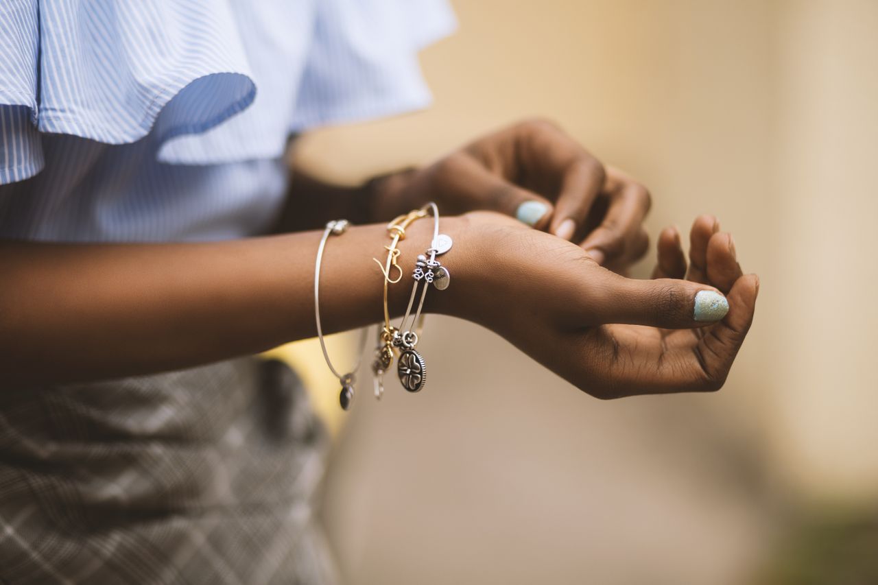 A woman wearing multiple charm bracelets with different metals.