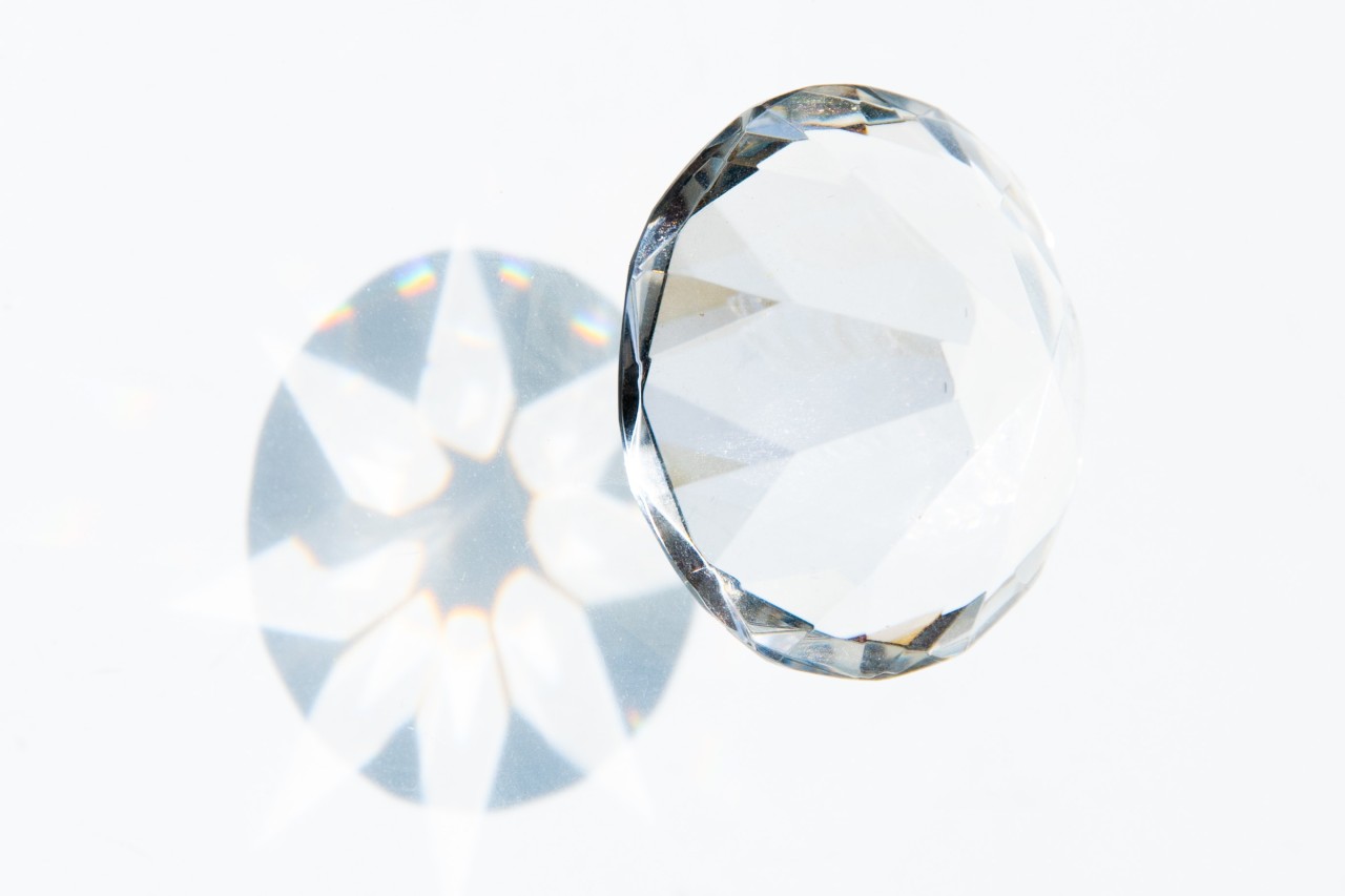 a round cut diamond casting shadows onto a white background