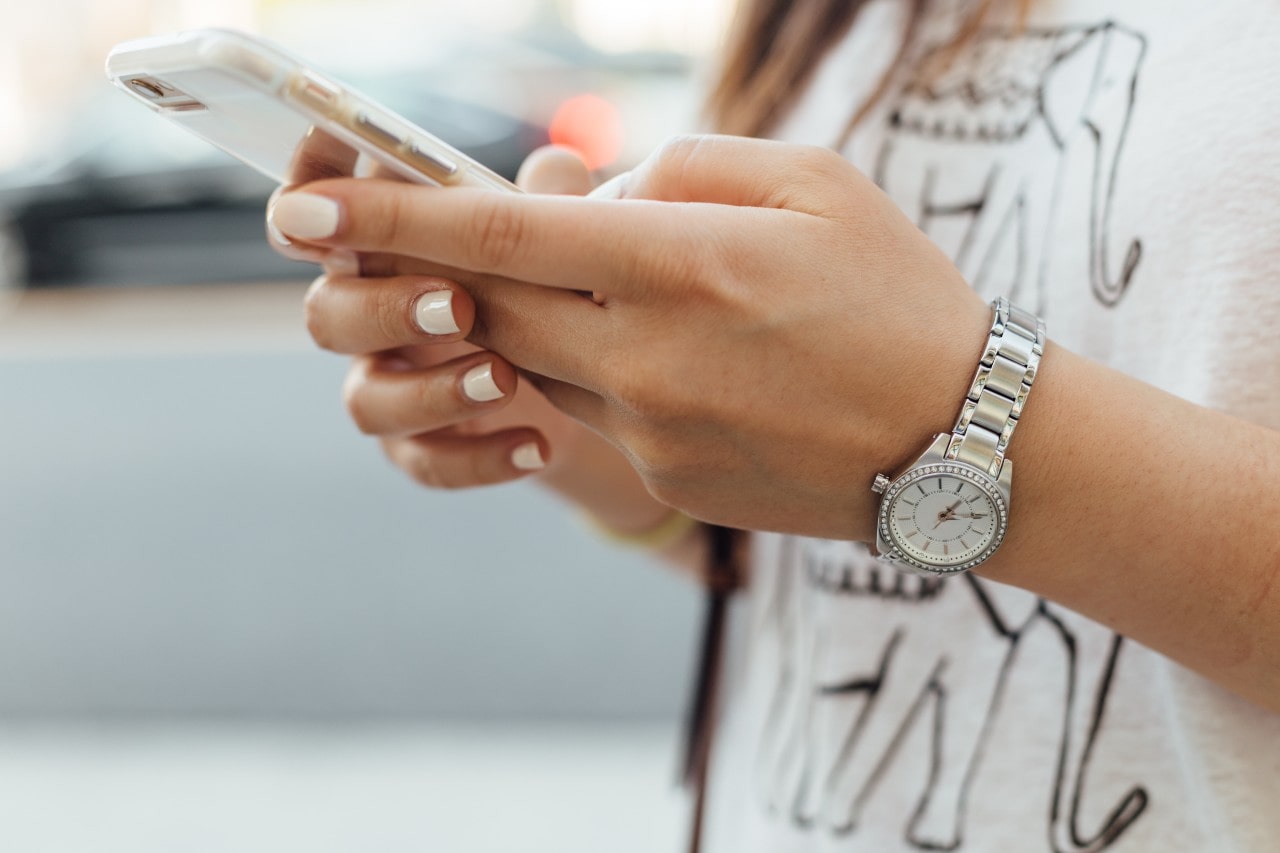 a woman looking at her phone and wearing a diamond studded watch