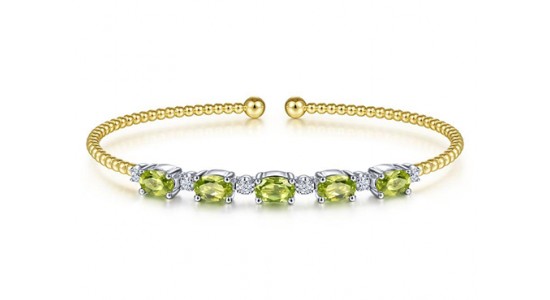 a yellow gold cuff bracelet featuring peridot and diamonds