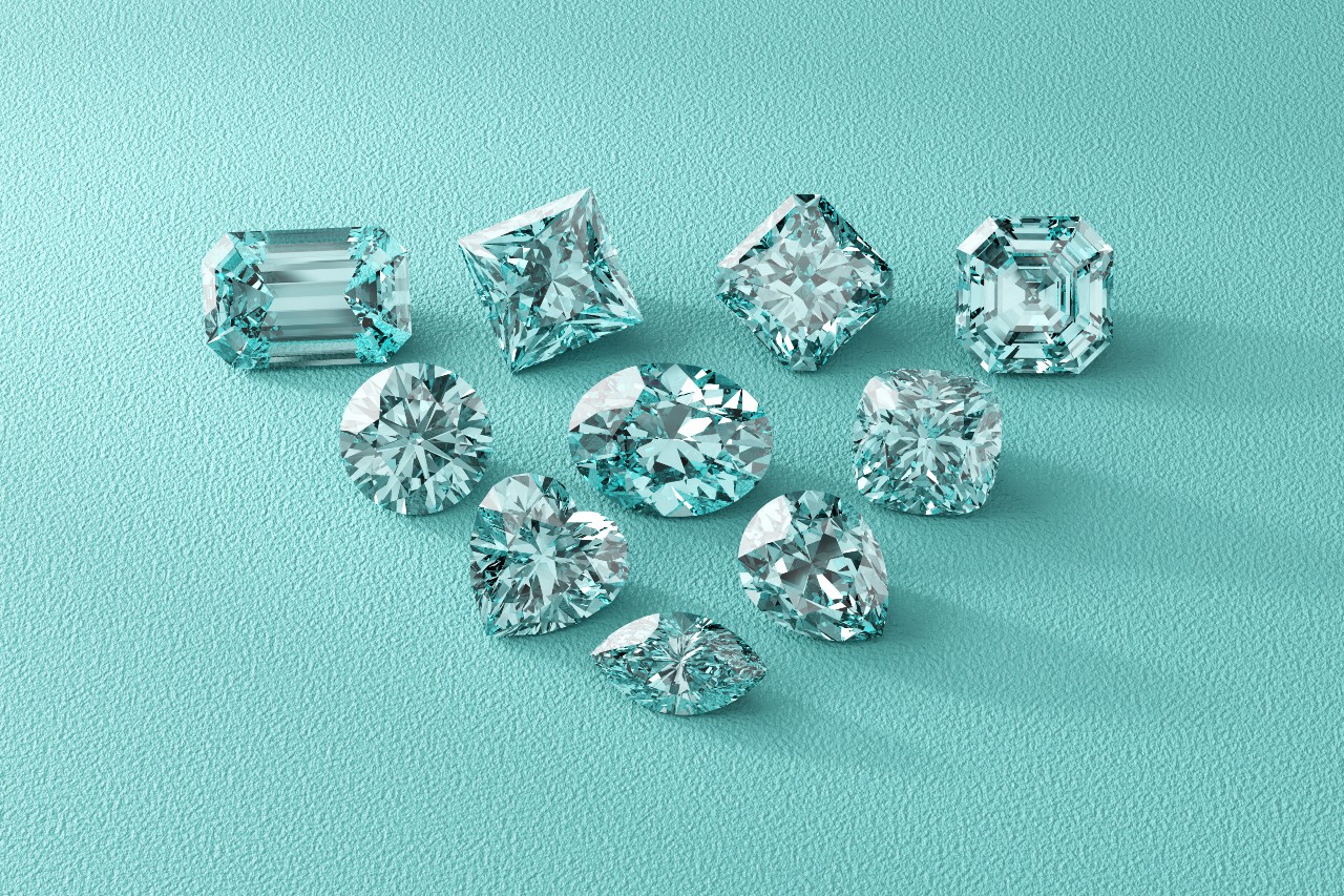 A group of diamonds with different cuts on a turquoise surface.