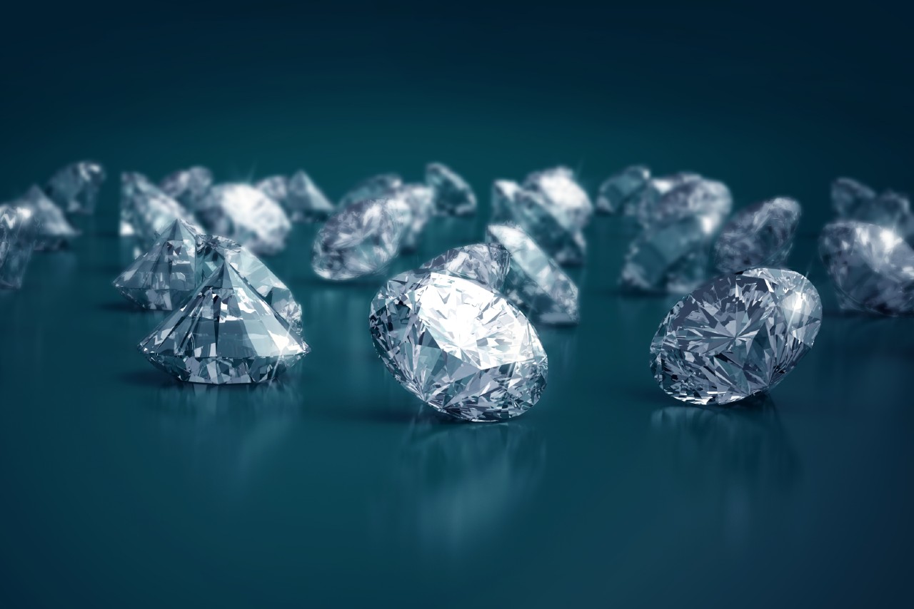 A group of round-cut diamonds sit on a blue reflective surface.