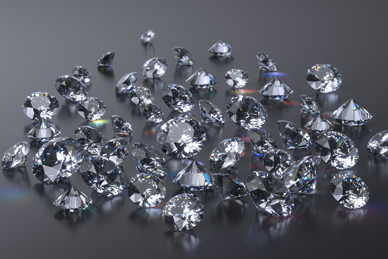 A group of diamonds reflect light while sitting on a gray surface.