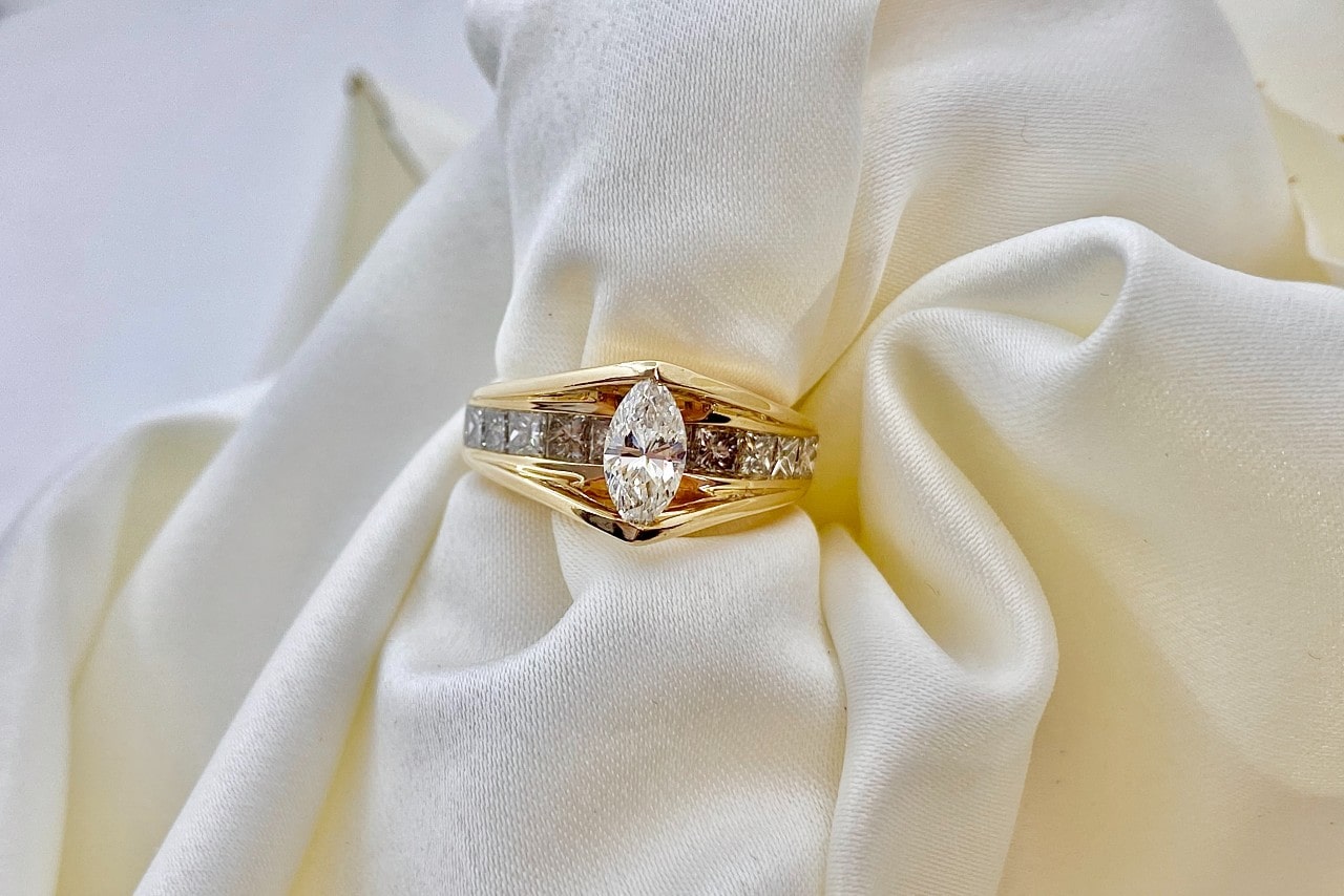 A vintage marquise cut diamond ring sits on a white cloth napkin.
