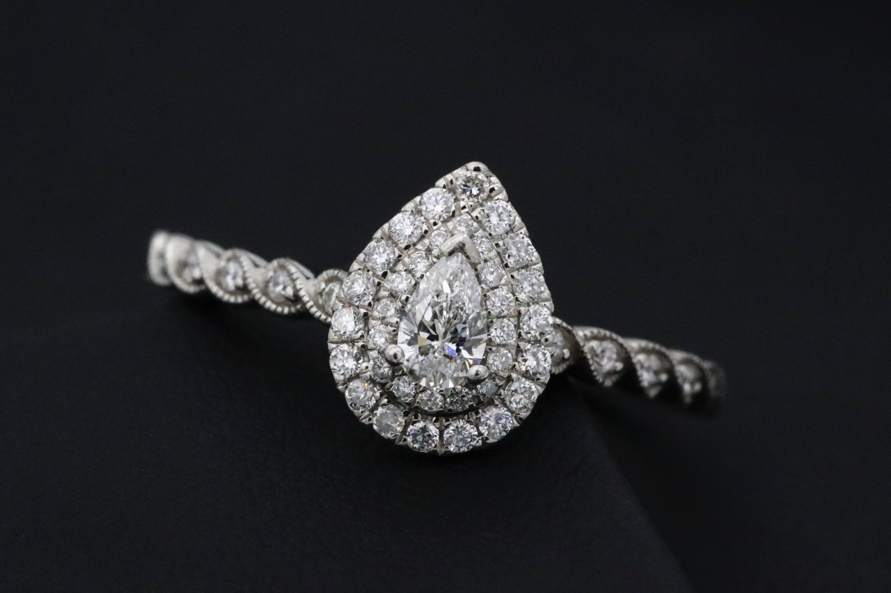 A vintage halo engagement ring with a pear-shaped diamond center stone on display.