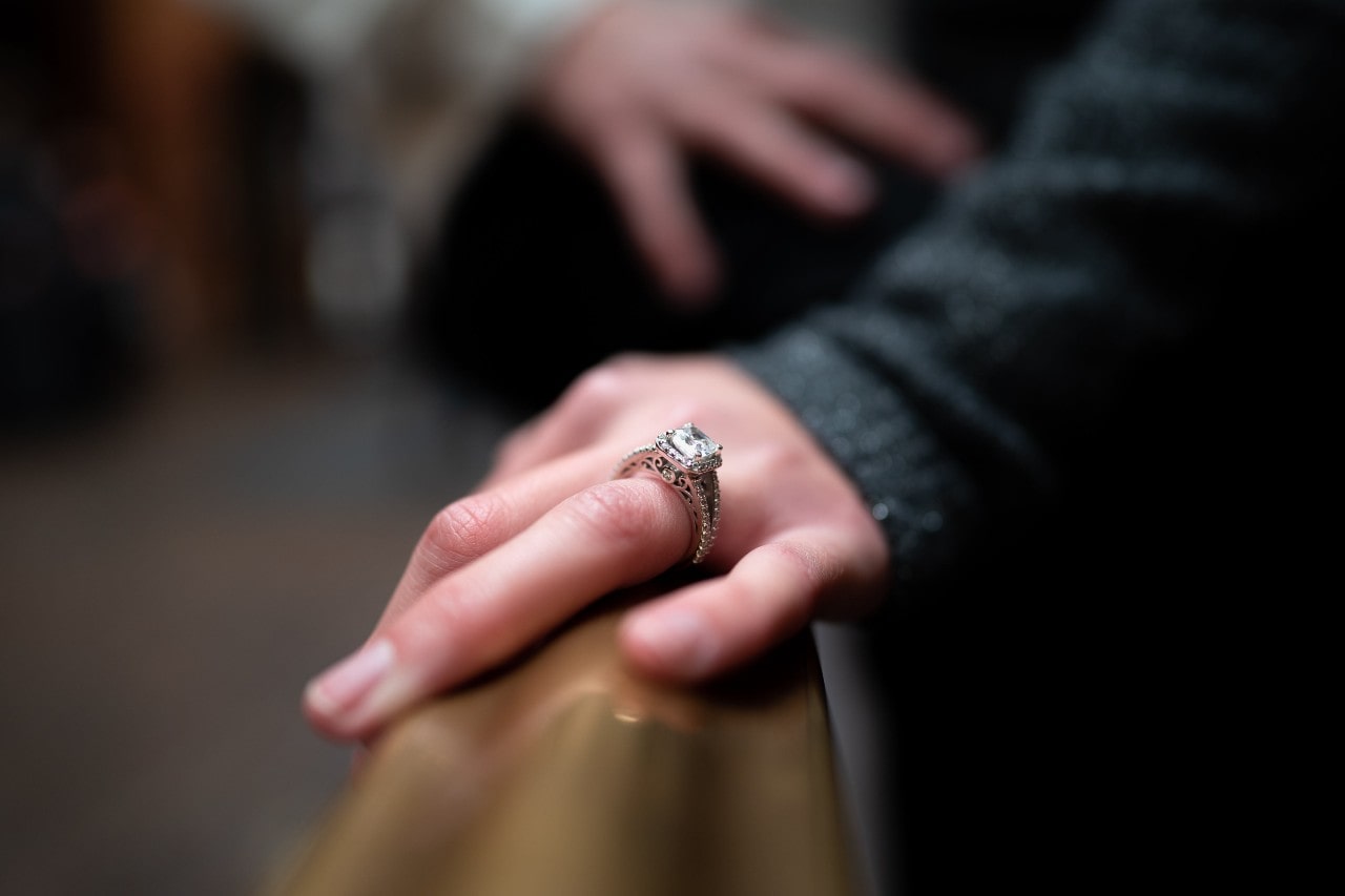 a woman’s hand on a bannister wearing a vintage engagement ring